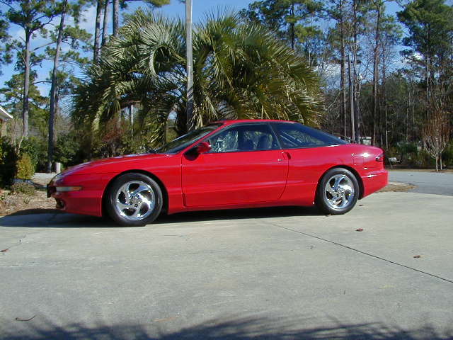 Red 1997 Ford Probe coupe, side view, parked on concrete driveway