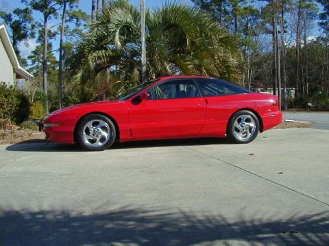 1997 Ford Probe - Side view of a red 1997 Ford Probe coupe parked on a concrete surface.