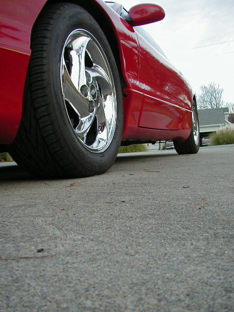 1997 Ford Probe - The side profile of a red sports car is visible, focusing on the front wheel and the lower body panels.