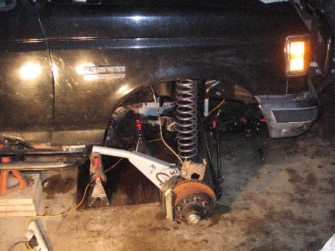 1988 Ford Bronco - Front suspension work on a black 1988 Ford Bronco, with the coilover and brake components visible.