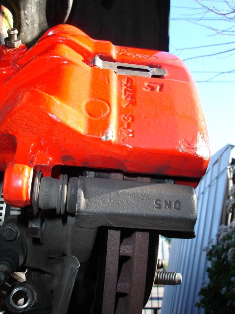 1993 Ford Taurus - Close-up of a red brake caliper with a black brake pad, revealing the part number DNS.