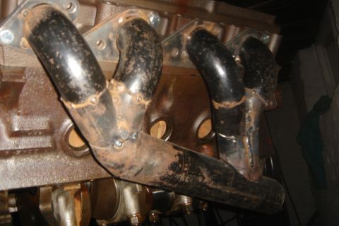 1969 Ford Mustang - Exhaust manifold bolted to an engine block, showing signs of rust and wear.