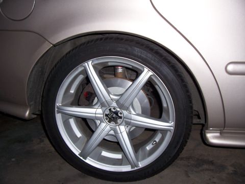 1998 Mercury Sable - Close-up of a tan car's rear wheel and fender area, showing an aftermarket wheel.
