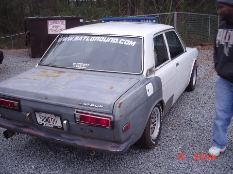 1994 Mazda 626 - Rear view of a Datsun 510 sedan, showing primer gray bodywork on the rear quarter panels.