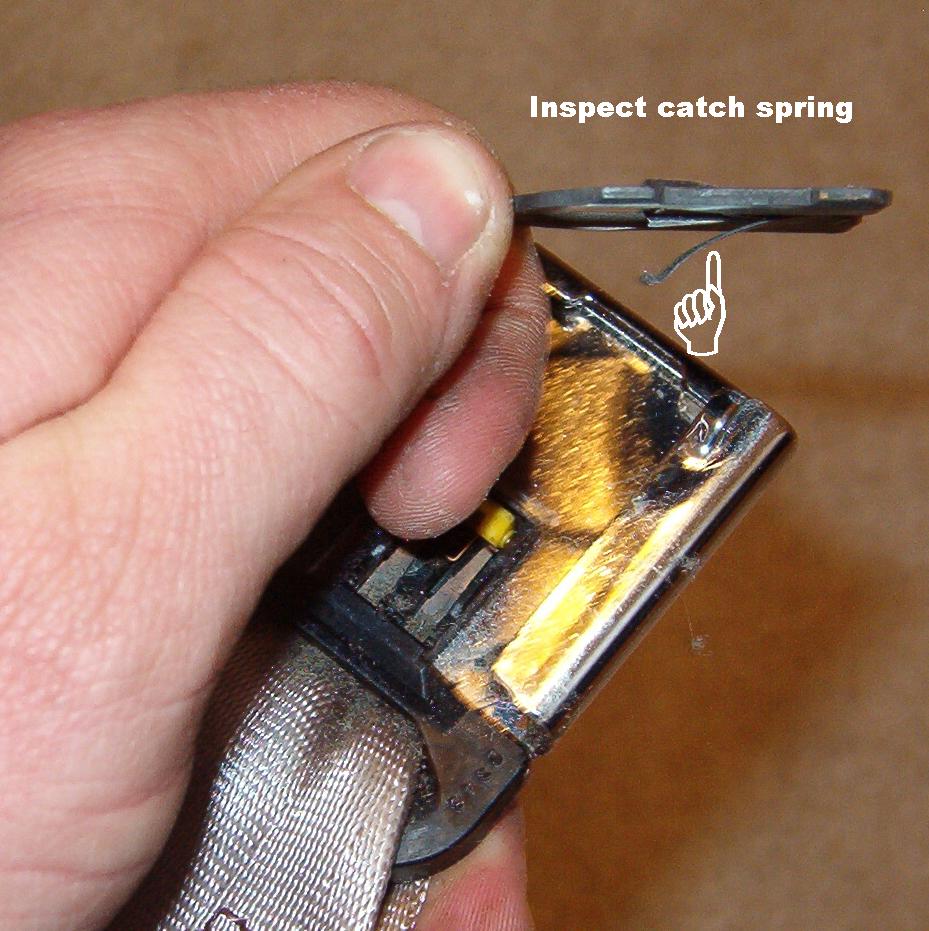 Since I also wanted to wash the seat belts, I disassembled the buckle.

It's common for this spring to fatigue & break, which can lock the buckle.  But it's common to all Fords with this shape of buckle, so it's easy to find one in a junkyard & swap it in.  Just be sure to get the spring from the same side that you need since the driver's buckle parts are all specific to fit with the switch.
