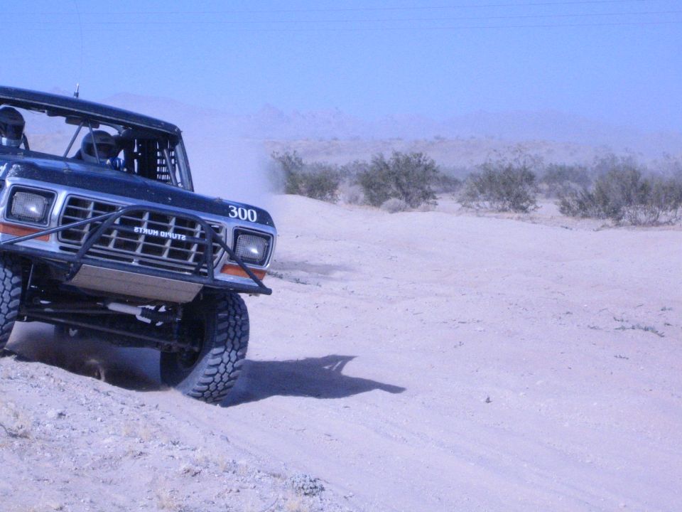 Close front view of black race truck number 300 with brush guard in sand