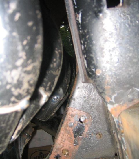 1969 Ford Mustang - This image shows a close-up view of rusty metal brackets and thick black hoses, likely part of a vehicle's suspension or frame.