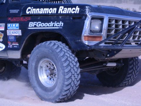 1990 Ford Bronco - close view of a black race truck's front wheel and fender displays "Cinnamon Ranch", BFGoodrich and sponsor decals.