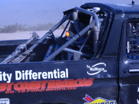 1990 Ford Bronco - bed and roll cage of a black race truck show shocks and decals reading "City Differential" and "66-79 Ford Broncos".