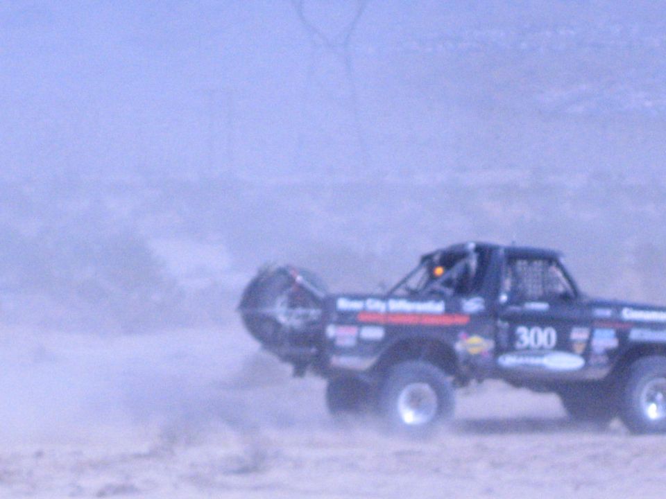 Off-road race truck 300 with front wheels lifting on a desert jump