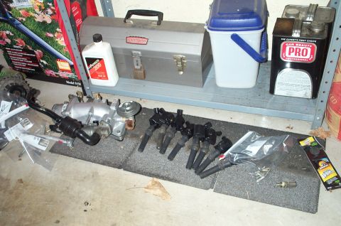 1998 Ford Crown Victoria - Engine parts including an intake manifold and spark plugs are displayed on the floor.