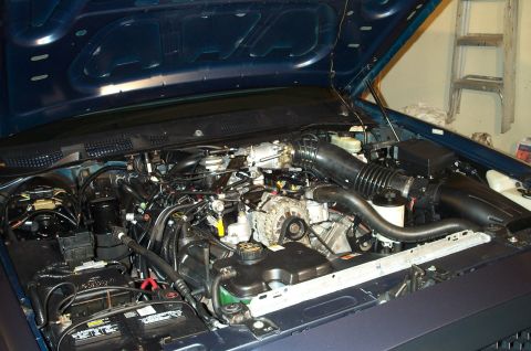 1998 Ford Crown Victoria - The engine compartment of a dark blue vehicle is shown with the hood raised.