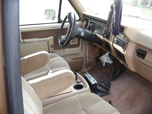 Tan interior of a Ford truck with manual shifter and bucket seats