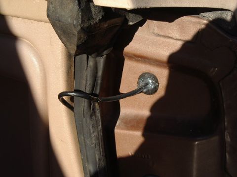 1985 Ford Bronco - Detail of a vehicle's interior door latch mechanism, showing a wire and ball component.
