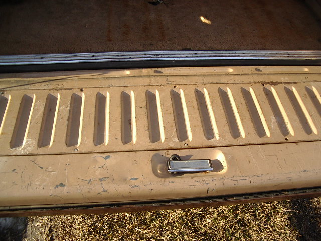 Tan ribbed pickup tailgate with chrome latch handle, viewed from inside the bed