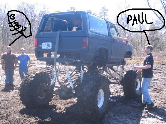 Rear view of a lifted SUV with large tires and custom suspension, mud-covered