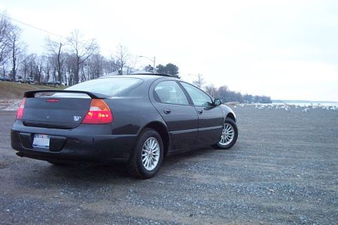 1999 Chrysler 300M - Rear view of a black 1999 Chrysler 300M parked on a gravel lot near a body of water.