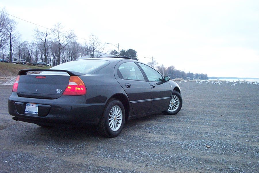 Black Chrysler 300M sedan with trunk spoiler parked on gravel by a shoreline