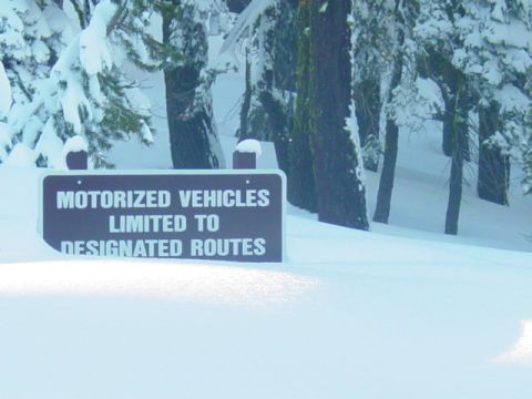 1986 Ford Bronco - A sign warns about motorized vehicle restrictions in a snowy forest landscape.