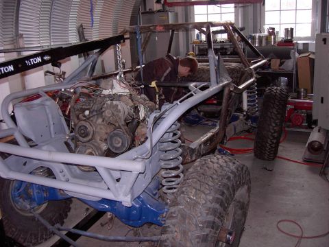1981 Ford F-150 - A person works on the engine of a custom off-road buggy in a workshop setting.