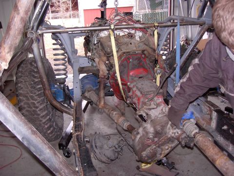 1981 Ford F-150 - Mechanic works on a vehicle's engine and drivetrain assembly being lifted out of the chassis.