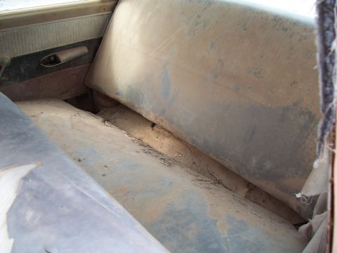 1955 Ford Customline - The interior of a car shows heavily worn seats and a dirty door panel.