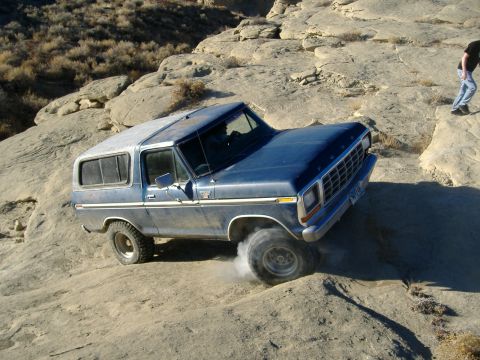 1978 Ford Bronco - Blue 1978 Ford Bronco navigating a challenging off-road course on a sunny day.