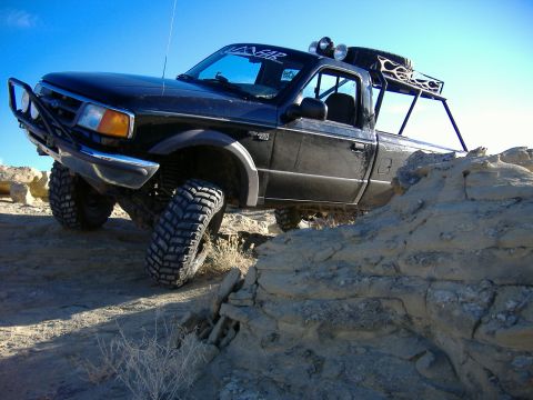1978 Ford Bronco - Modified pickup truck navigating rocky terrain under a clear blue sky.