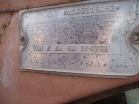 1955 Ford Customline - A close-up view of a weathered Ford VIN plate, showing stamped identification numbers and the Ford logo.