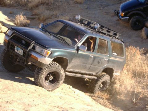 1978 Ford Bronco - A green SUV navigates a challenging off-road course, with another vehicle visible in the background.