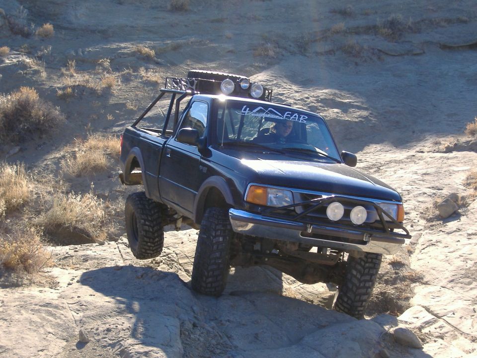 Black pickup truck with off-road modifications driving over rocks