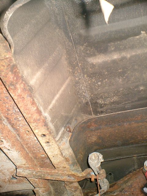 1989 Ford Bronco - The underside of a vehicle shows extensive rust on the frame and suspension parts, indicating age and wear.