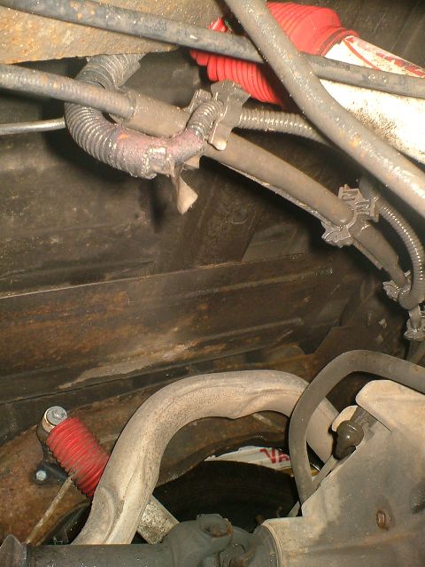 1989 Ford Bronco - Close-up view of the underbody of a vehicle, showing wiring, exhaust components, and a red shock absorber boot. The registry claims it is a…