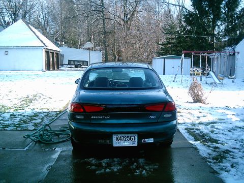 1997 Ford Escort - The rear of a dark green 1997 Ford Escort LX is visible in a snowy residential setting.