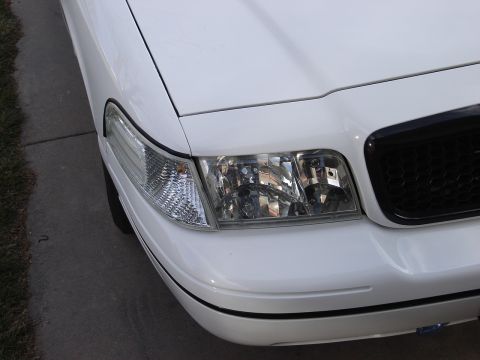 2000 Ford Crown Victoria - Front corner view of a white 2000 Ford Crown Victoria, showing the headlight and grille detail.