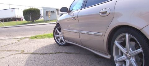 1998 Mercury Sable - The side profile of a tan 1998 Mercury Sable sedan is visible, aftermarket wheels and a chrome trim line.