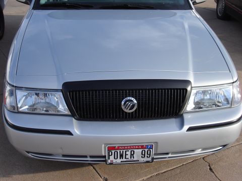 2000 Ford Crown Victoria - Front view of a silver Mercury Grand Marquis, a black grille and Nebraska license plate reading 'POWER 99'.