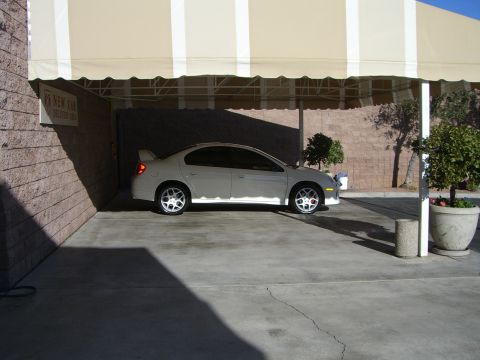 1996 Ford Probe - A silver Dodge Neon SRT-4 is parked under a beige and white striped awning.