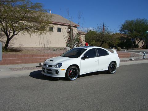 1996 Ford Probe - A white Dodge Neon SRT-4 is parked on the street in front of a house on a sunny day.