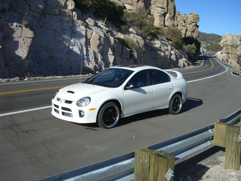 1996 Ford Probe - A white Dodge Neon SRT-4 drives on a winding road through a rocky, mountainous landscape.