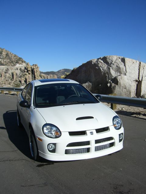 1996 Ford Probe - A white Dodge Neon SRT-4 is parked on the side of a road with a mountainous landscape in the background.