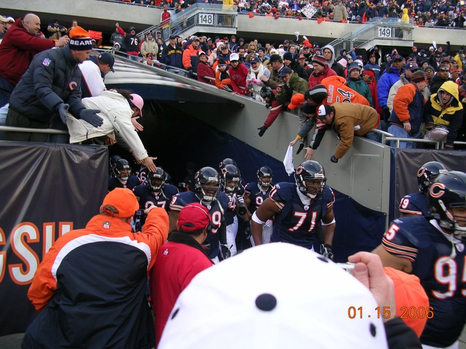 Football players in uniform run onto the field through a tunnel