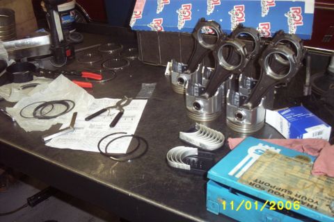 1967 Ford Galaxie - Engine components and tools are organized on a workbench, suggesting an ongoing engine rebuild or repair.