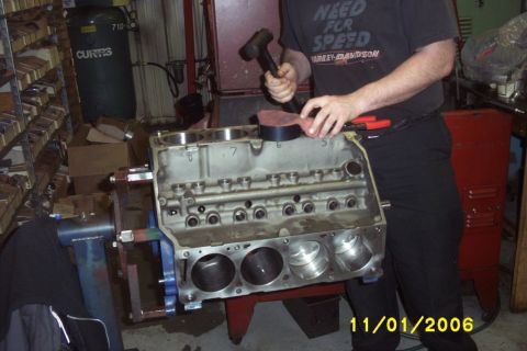 1967 Ford Galaxie - Engine block on a stand, being worked on with a mallet and other tools.