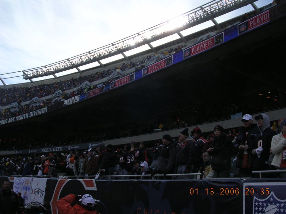 People in a stadium watching a football game. Signs say 'PLAYOFFS' and '2005 AFC NORTH DIVISION'