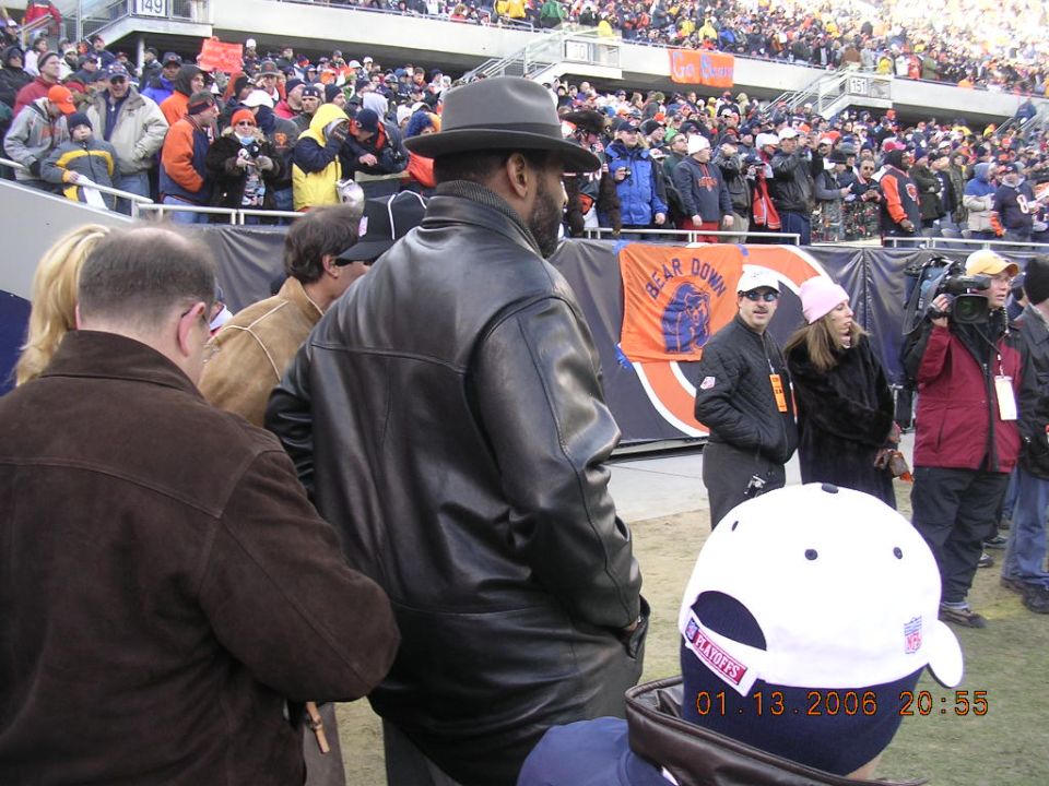 People in stadium seating, some wearing hats and jackets, with a banner that says "BEAR DOWN"