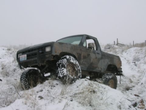 1984 Ford Bronco II - A heavily modified SUV navigates a snowy incline with large off-road tires.