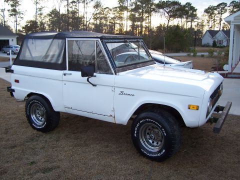 1974 Ford Bronco - This 1974 Ford Bronco features a white exterior and a black soft top, captured in a 3/4 front view.