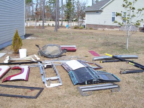 1978 Ford Bronco - Various vehicle parts are laid out on the grass in front of a residential house and fence.