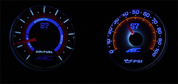 Blue-lit aftermarket air/fuel ratio and oil pressure PSI gauges in the dark